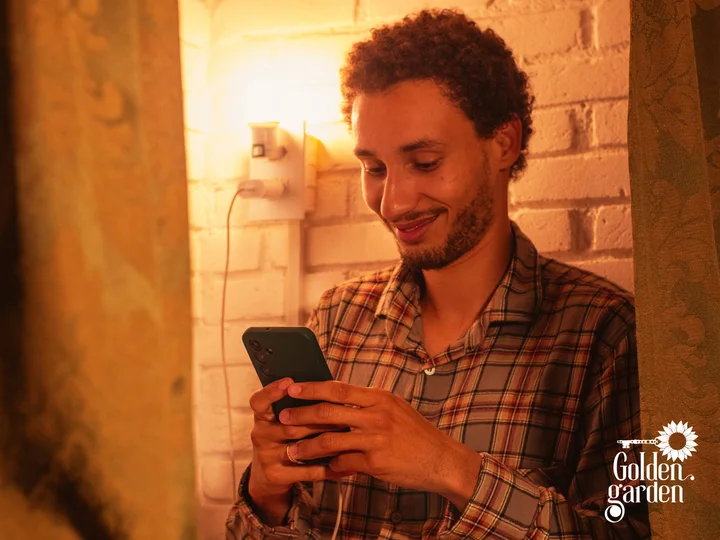 Hóspede usando o celular ao lado da tomada da cama